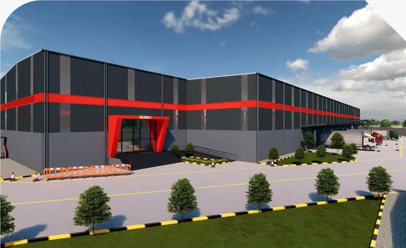 A modern industrial warehouse and fulfillment center designed by a premier real estate company in Kolkata, featuring a grey and red facade with cargo trucks parked at the loading bays.